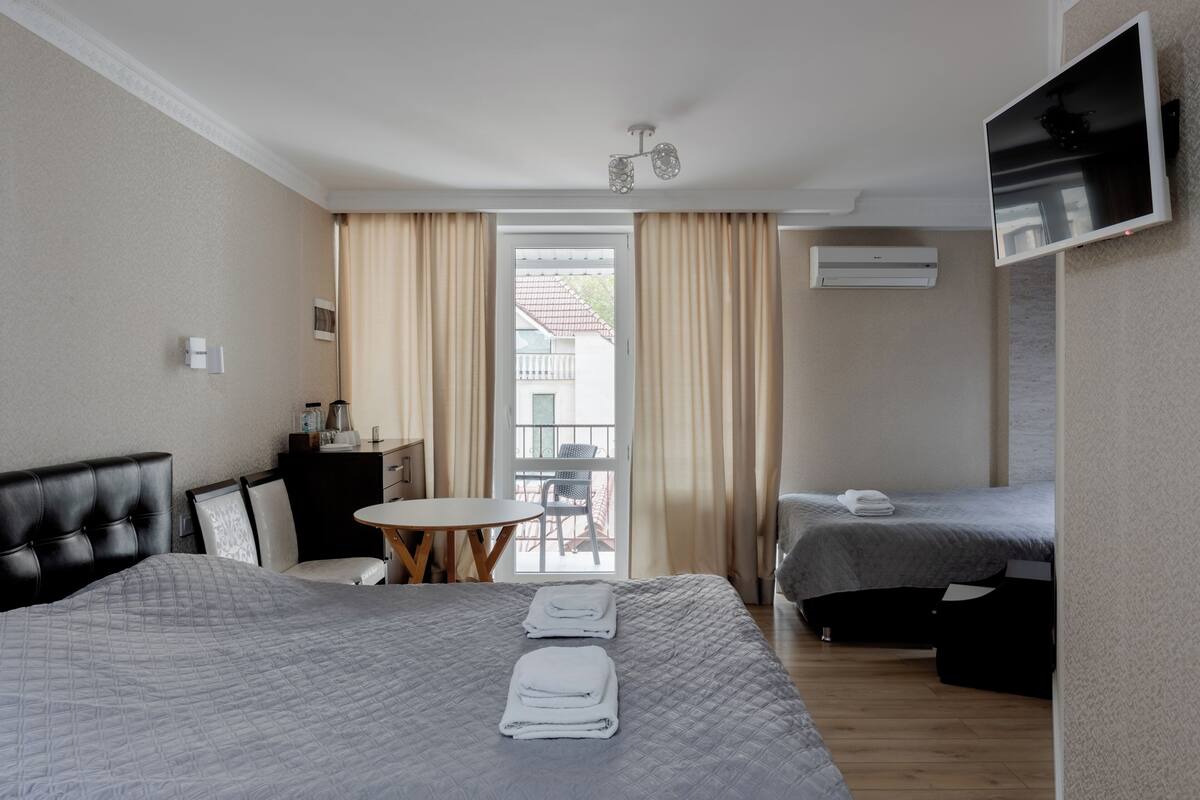 Een hotelkamer met een bed, een bureau, een stoel, een televisie en een balkon.