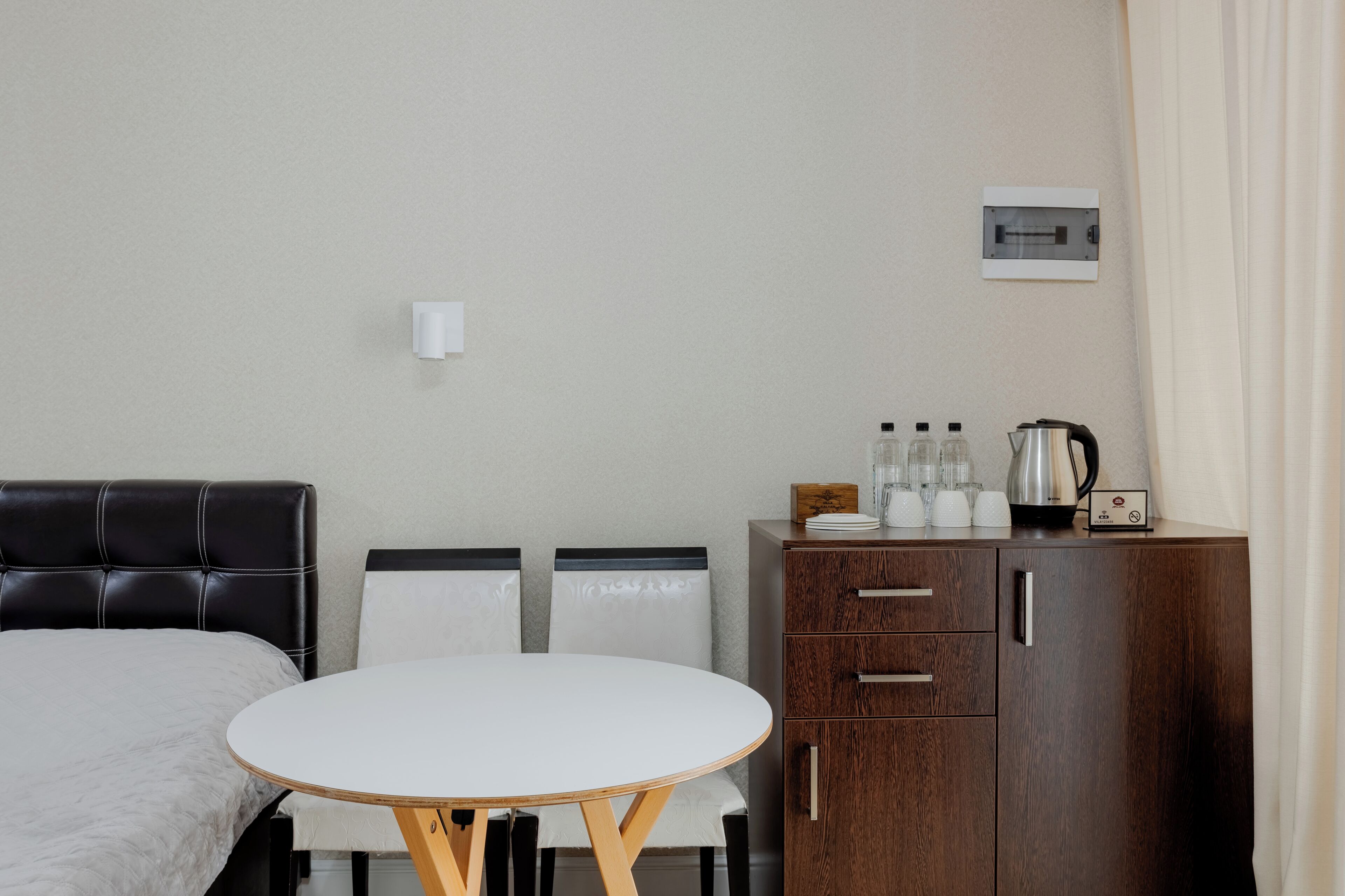 Habitación de hotel con cama, una mesa redonda, dos sillas, un armario de madera y una cafetera.