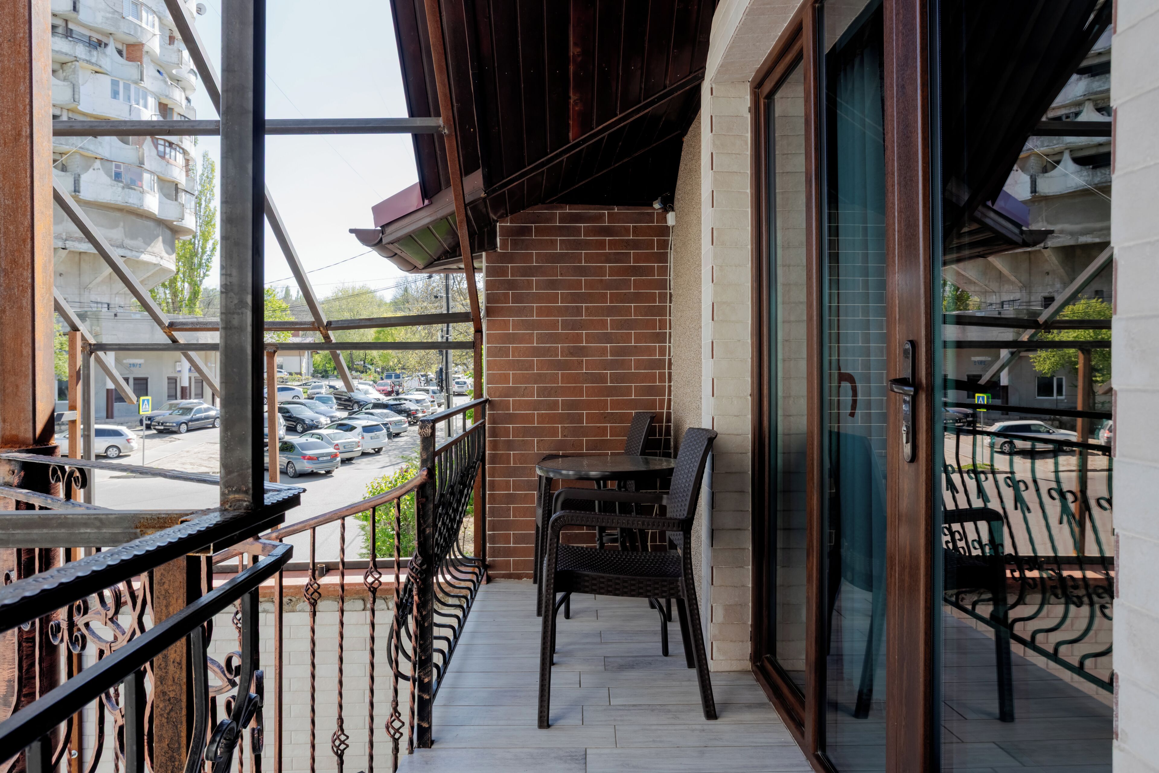 A balcony with a brick wall, metal railing, and a table with chairs.