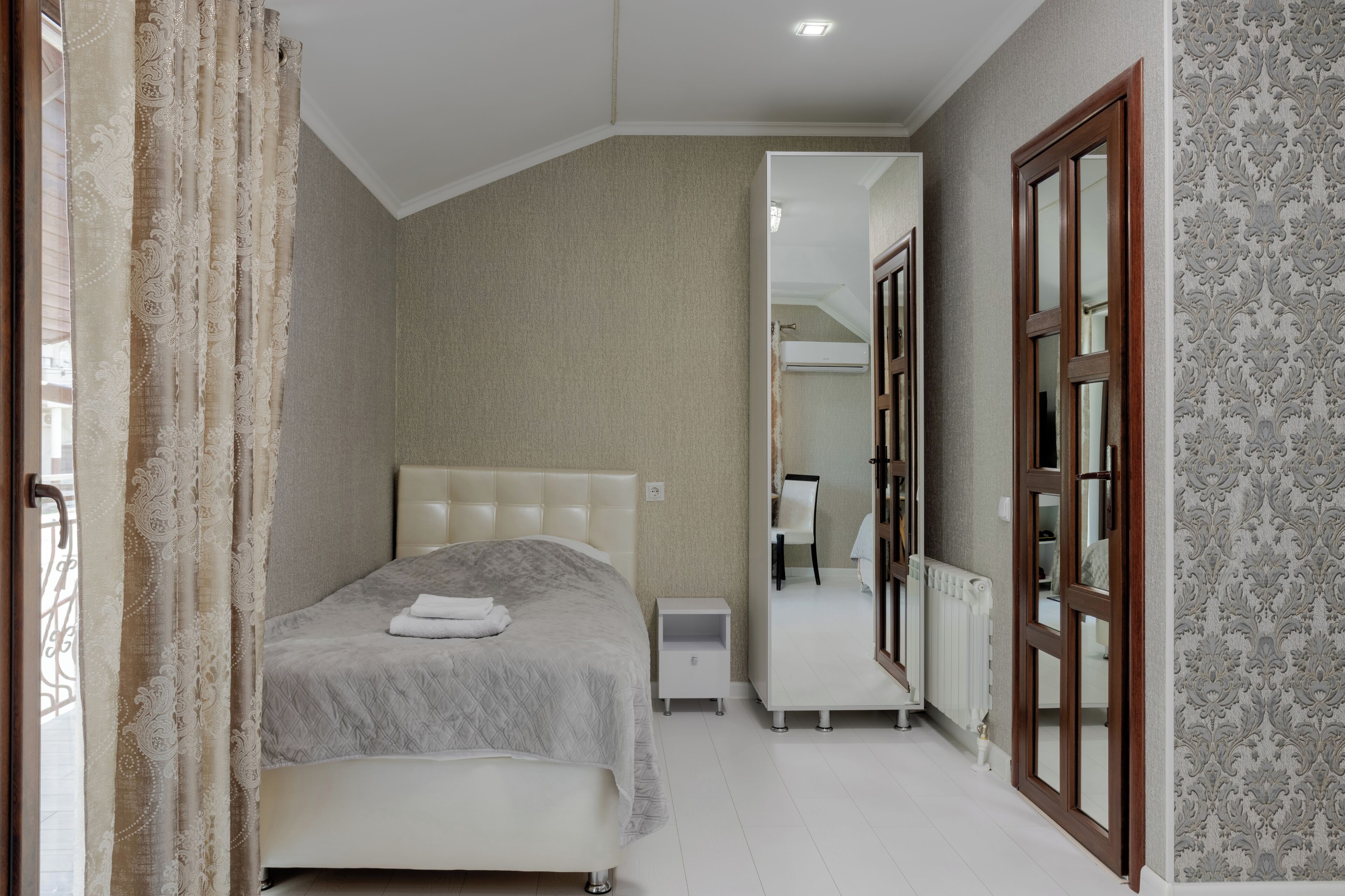 Un dormitorio con cama, mesita de noche y espejo.