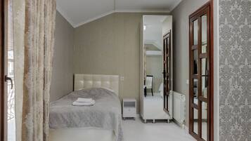 Un dormitorio con cama, mesita de noche y espejo.