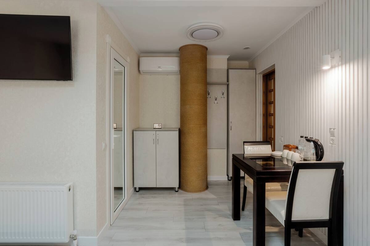 Een moderne kamer met een flatscreen televisie, een klein kastje, een rieten mand, een tafel met stoelen en een douche.