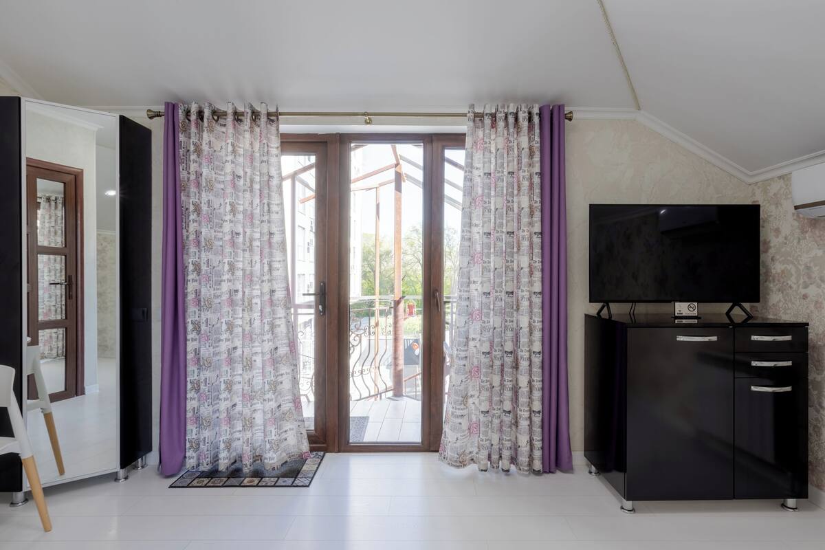 Een kamer met een schuifglasdeur, een zwarte entertainmentskast en een witte stoel.