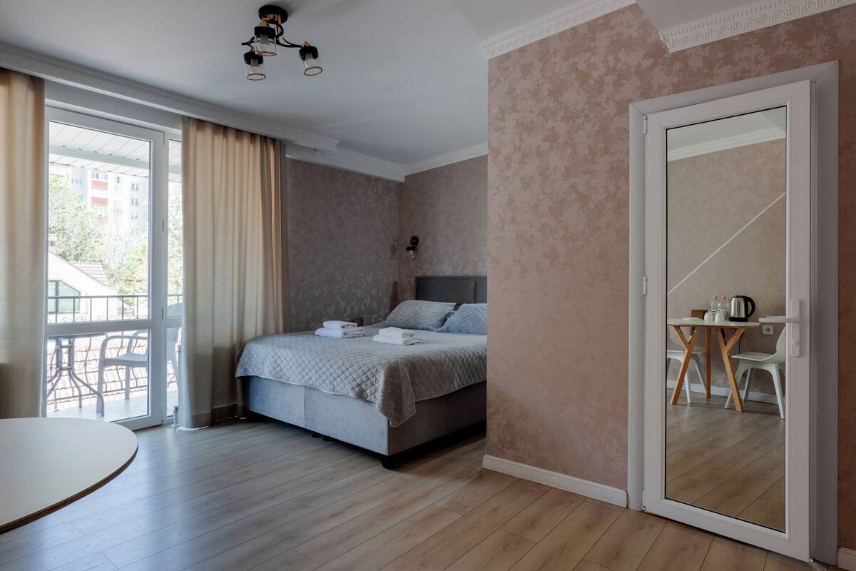 Een slaapkamer met een bed, een eettafel, een stoel, een schuifdeur en een balkon.