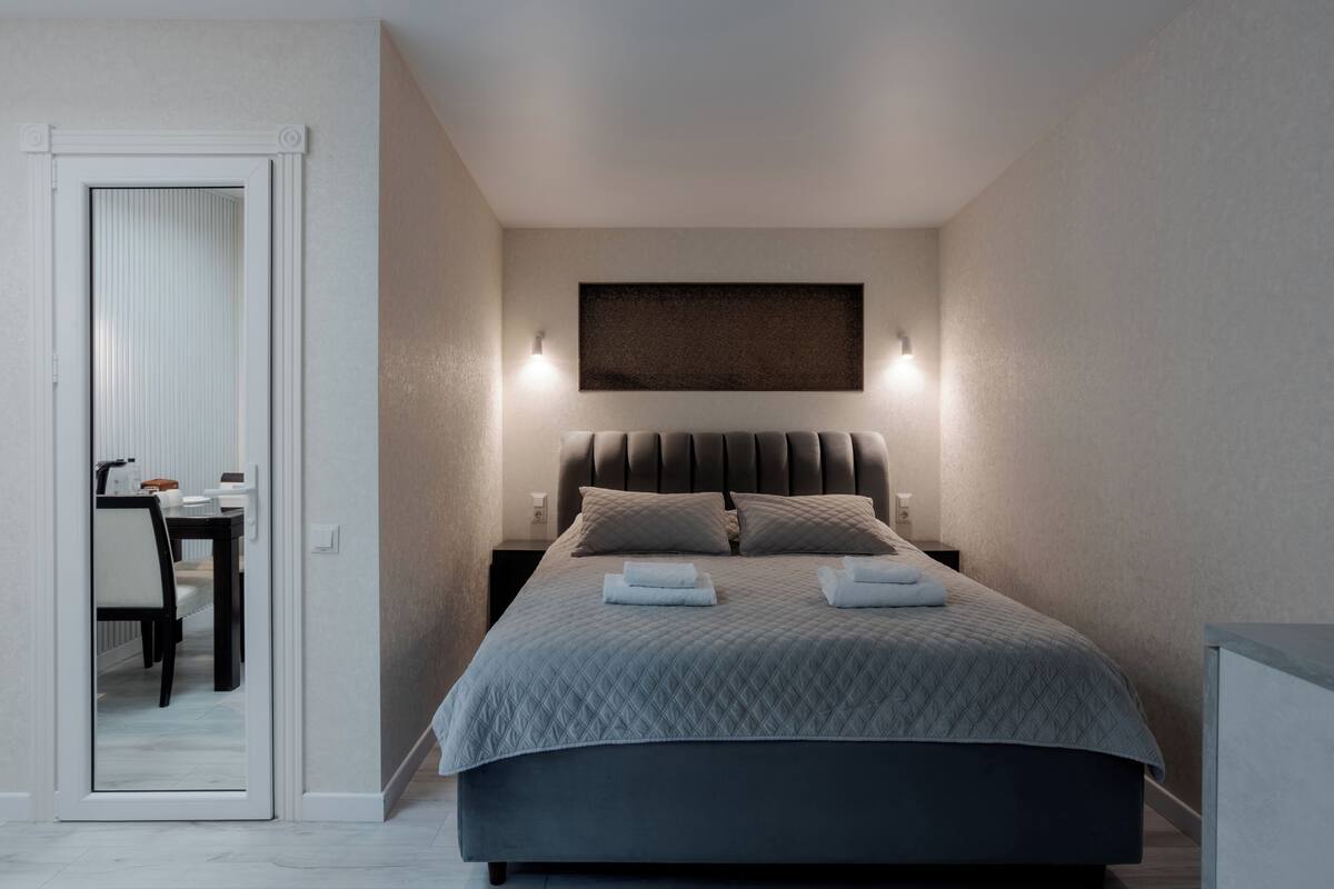 Een moderne slaapkamer met een bed, nachtkastjes en een spiegel.