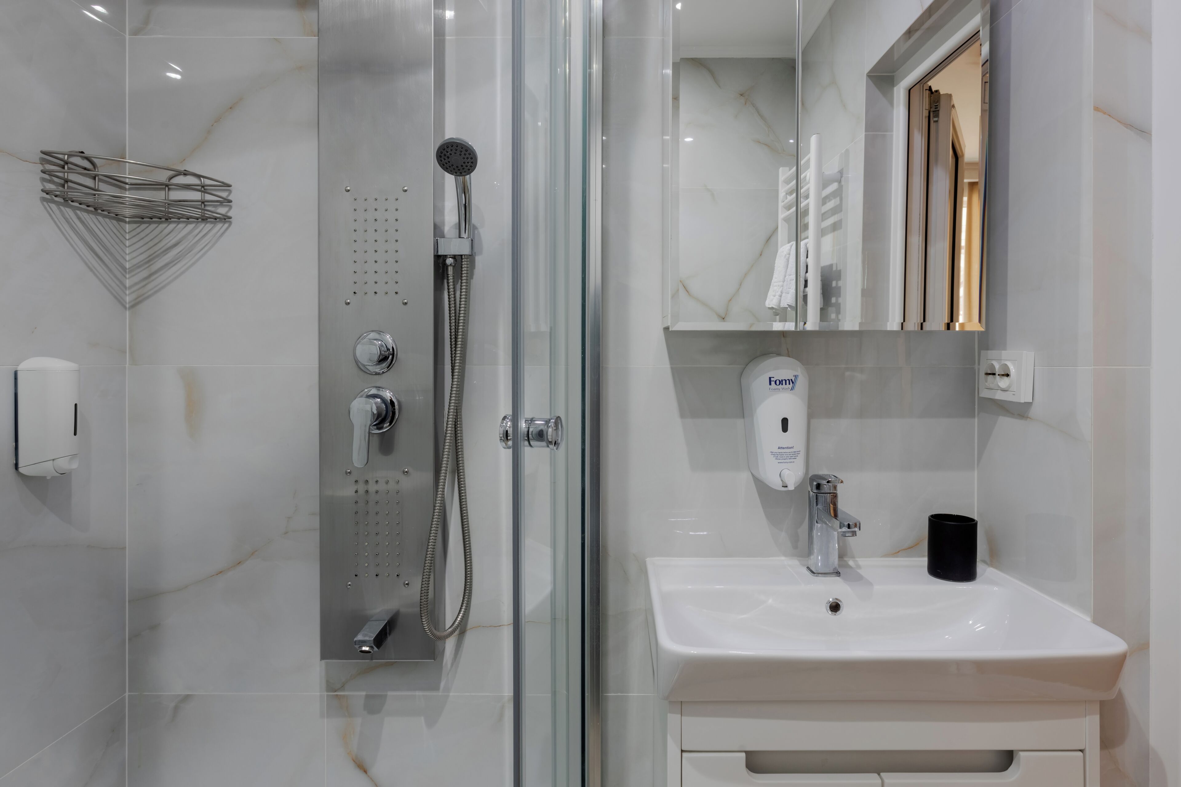 A modern bathroom with a glass-enclosed shower, a white sink, and a mirror above it.