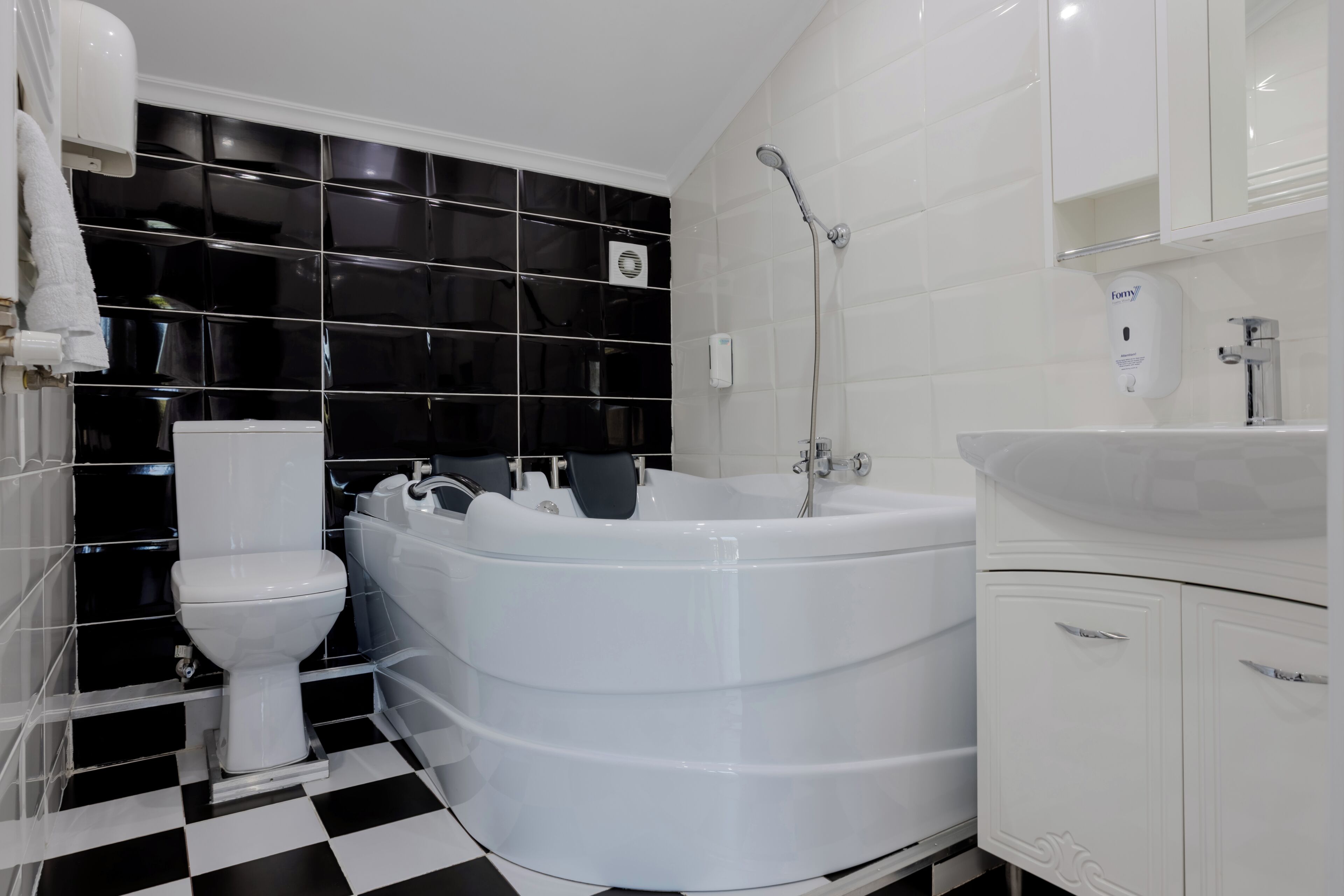 Et badeværelse med et hvidt toilet, et fristående badekar og en hvid vask med et spejl over.