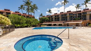 Um hotel com piscina, palmeiras e céu azul claro.