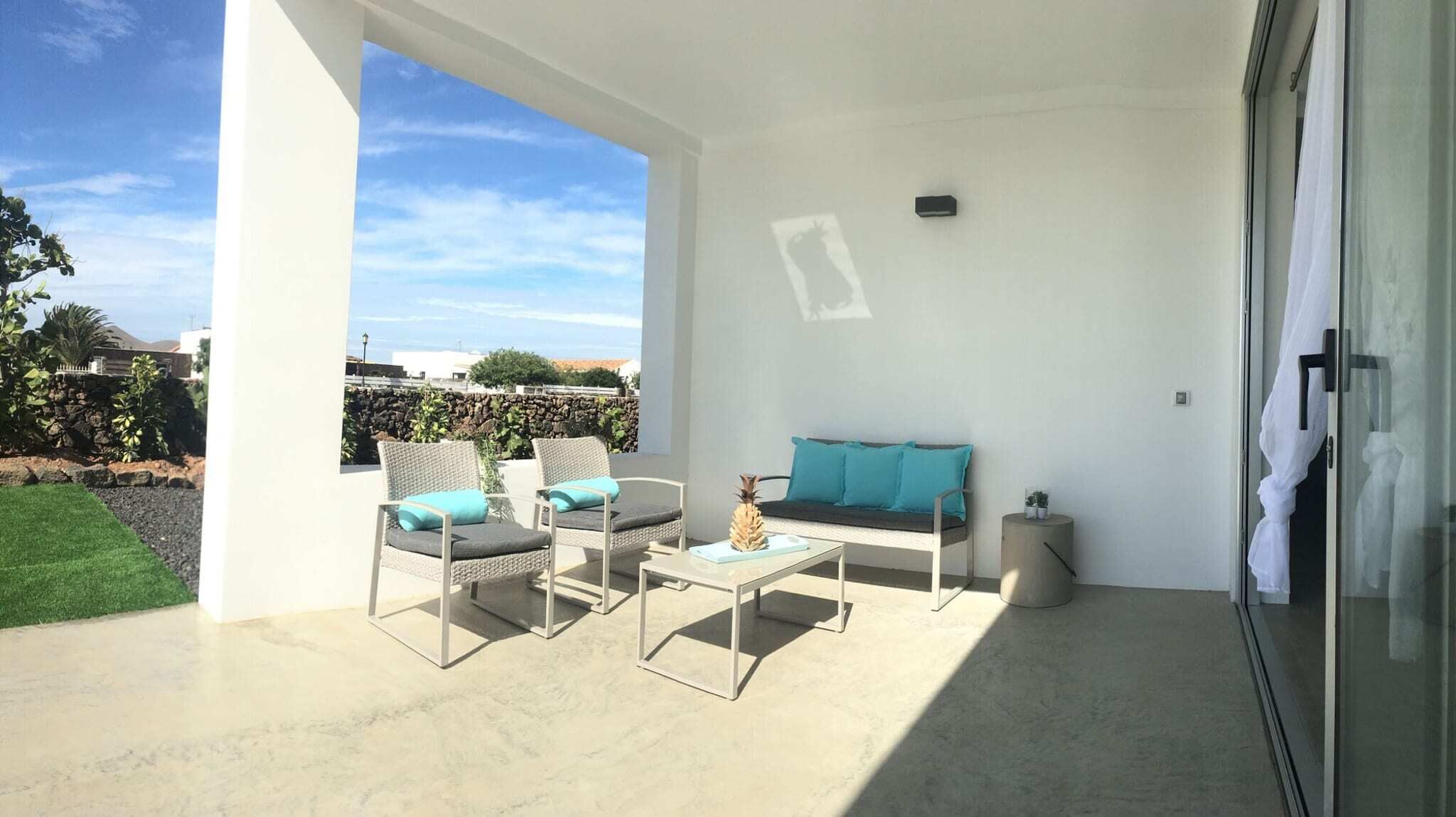 Eine moderne Terrassenanlage mit einer Couch, zwei Stühlen und einem kleinen Tisch.