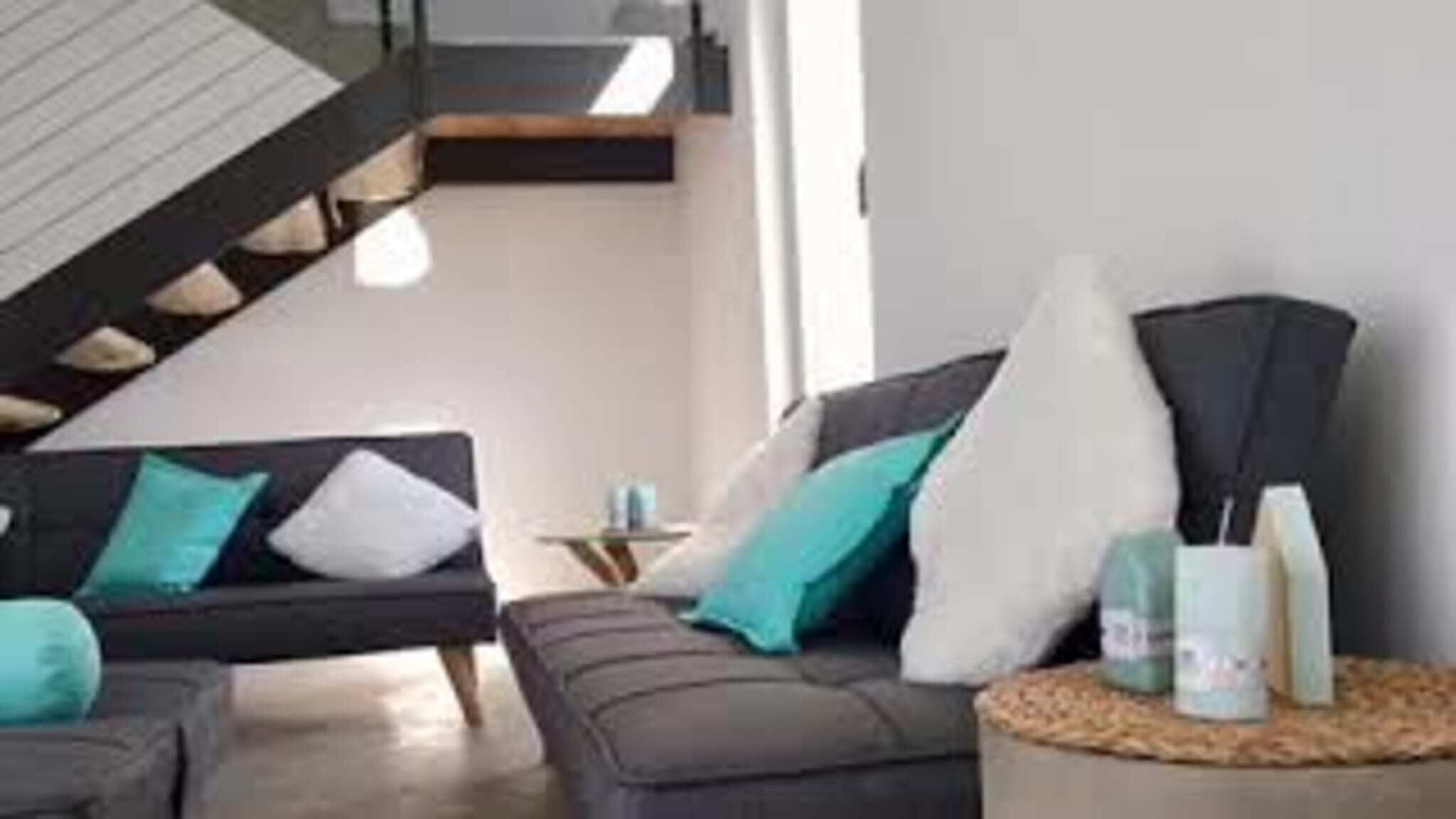Un salon moderne avec un canapé gris, une table basse et une lampe.