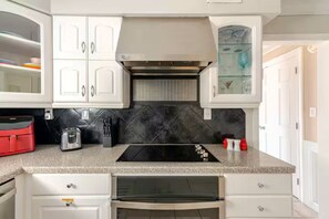 A kitchen with white cabinets, a black countertop, and a built-in oven. - The Sweet Spot! - Live Like a Local (Saint Matthews)