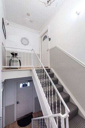 A staircase with white railings leading to a landing with a door and a small window.