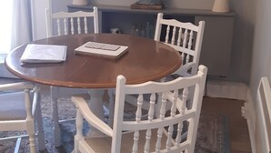 A dining area with a round wooden table, white chairs, a patterned rug, and a framed picture above the table. - Seahorse central Dartmouth Town 
 (Dartmouth)