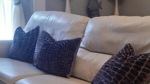 A light-colored sofa with patterned cushions, a framed picture on the wall, and a fish-shaped wall decoration. - Seahorse central Dartmouth Town 
 (Dartmouth)