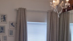A bedroom with a bed, curtains, a chandelier, and framed pictures on the wall. - Seahorse central Dartmouth Town 
 (Dartmouth)
