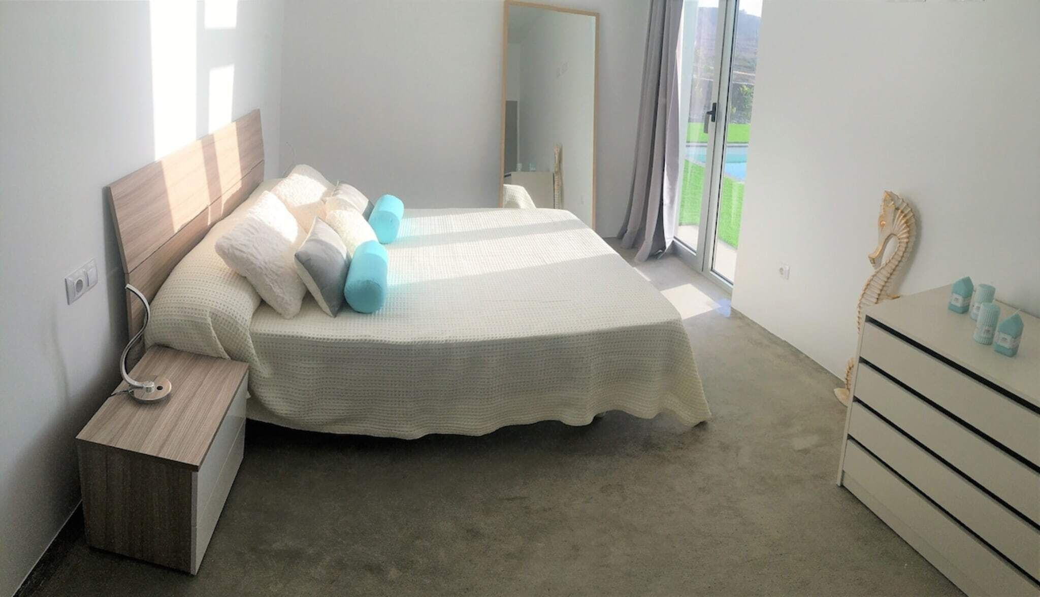 A bedroom with a bed, bedside table, dresser, and a mirror.