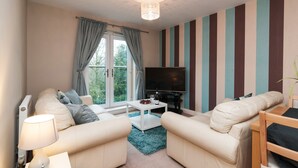 A modern living room with a sofa set, a coffee table, a TV, and a striped wall.