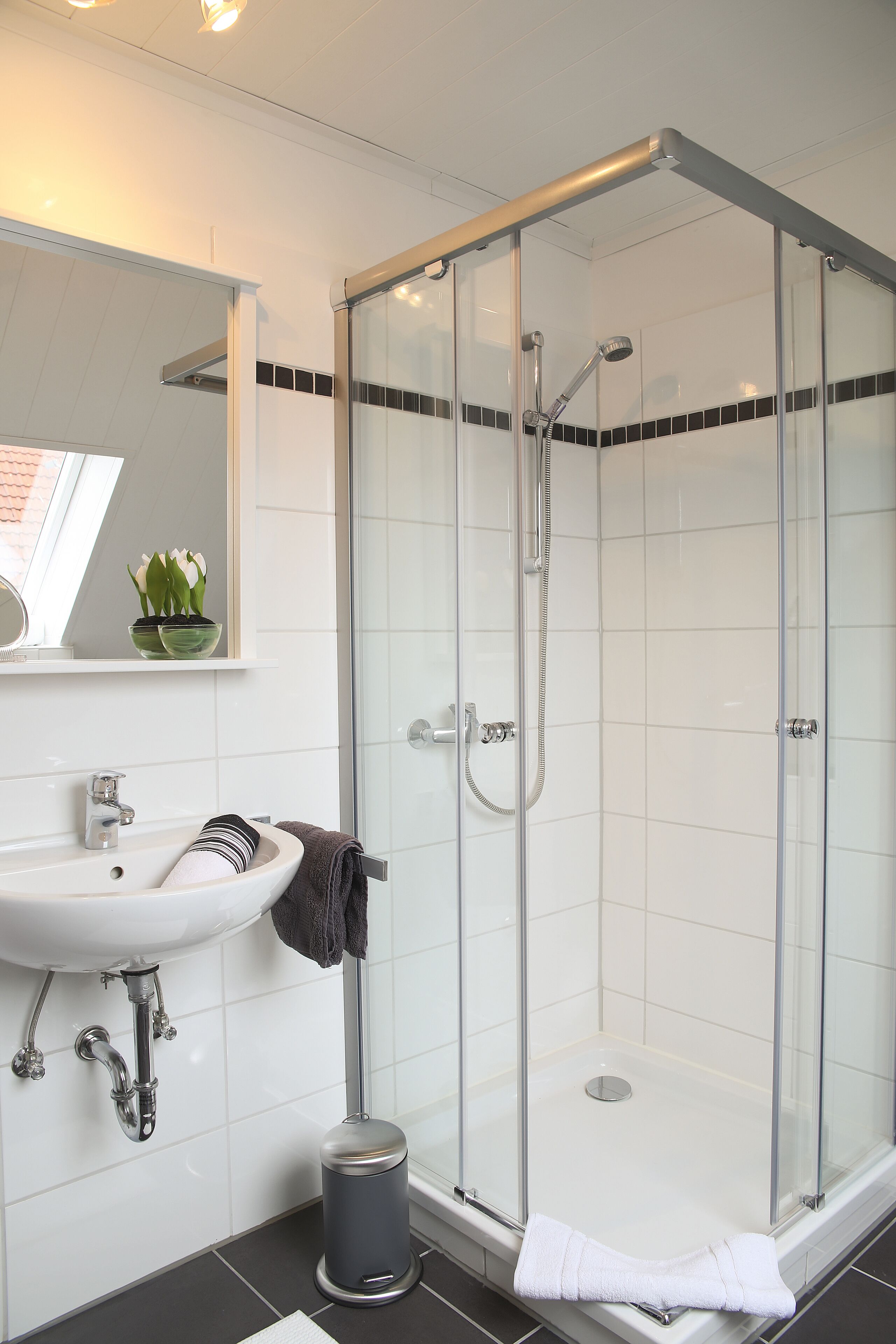 Un bagno moderno con cabina doccia in vetro, lavandino e specchio.