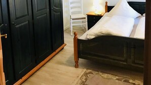 Un dormitorio con cama, armario, silla y mesita de noche.