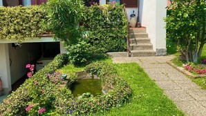 Una casa con jardín, un estanque y una escalera que lleva a la entrada.