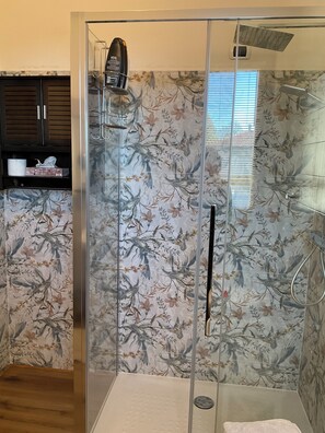 Ducha con azulejos florales, una toalla y un secador de pelo.