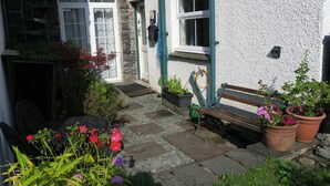 A stone pathway leading to a white building with a wooden bench and potted plants. - Keswick, Garden Apartment for 2. Excellent location.Convenient for all amenities (Keswick)