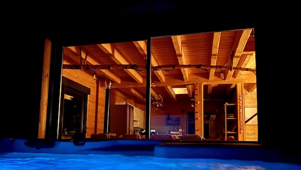 A wooden interior with a high ceiling and visible beams, a kitchen area, and a view through large windows. - Le Hygge Chalet Gerardmer 1-10 Pers (Anould)