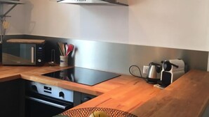 Eine Küche mit Dunstabzugshaube aus Edelstahl, einer Mikrowelle, einem Toaster und einer Obstschale auf der Arbeitsfläche.