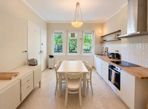 A modern kitchen with a central island, white cabinetry, and large windows.