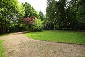 Une zone herbeuse avec un sentier de gravier menant à une zone boisée.