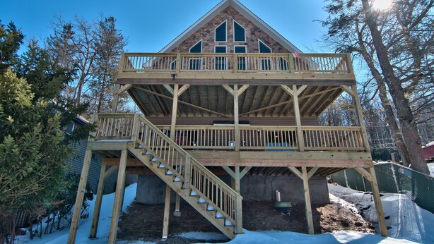 A two-story wooden cabin with a balcony and a staircase.