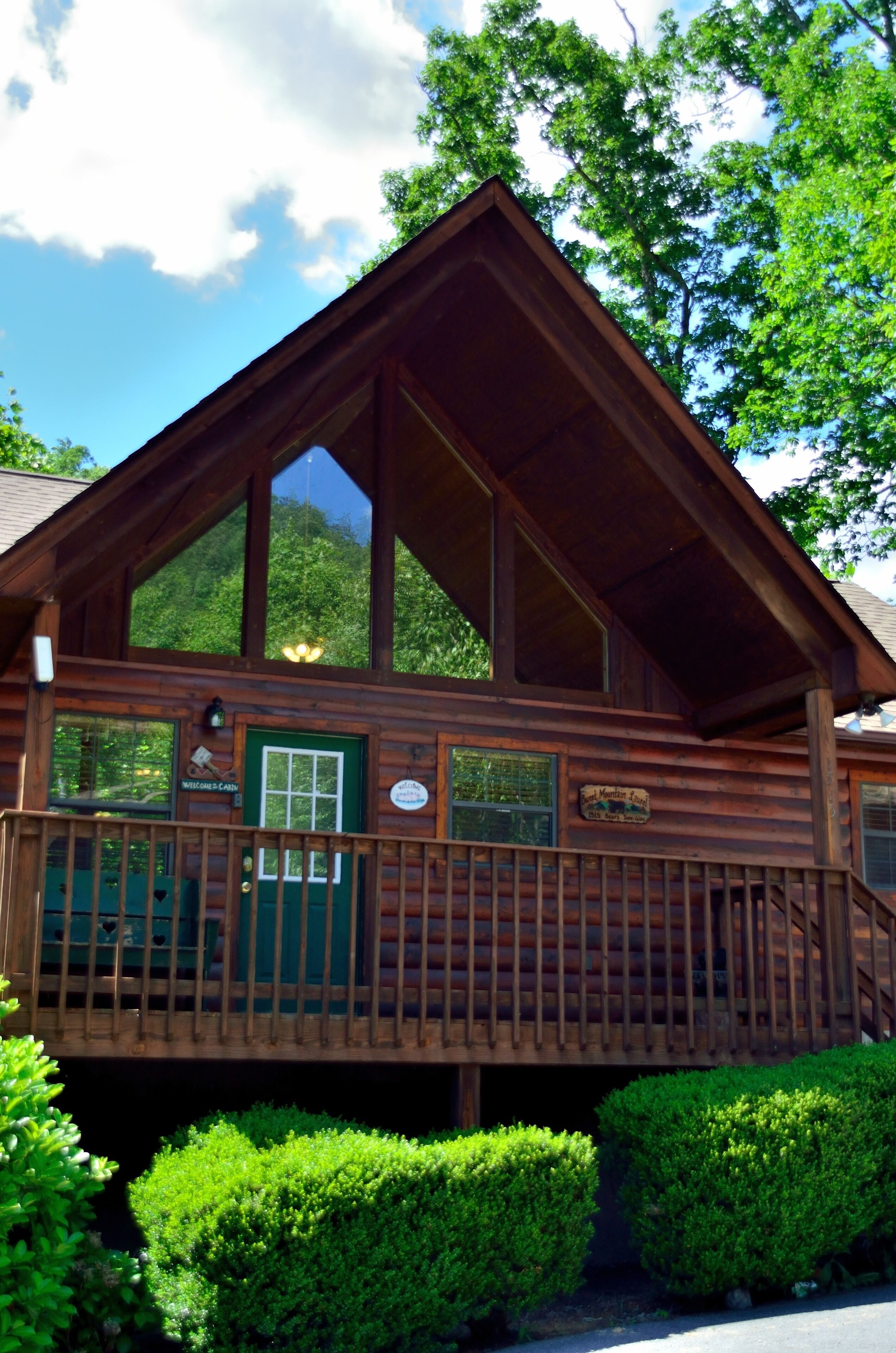 Eine Holzhütte mit Veranda, einer grünen Tür und einem Schild, auf dem 'Willkommen auf dem Campingplatz' steht.
