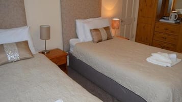 Ein Hotelzimmer mit zwei Betten, einem Nachttisch, einer Lampe, einem Holzschrank und einem Spiegel.