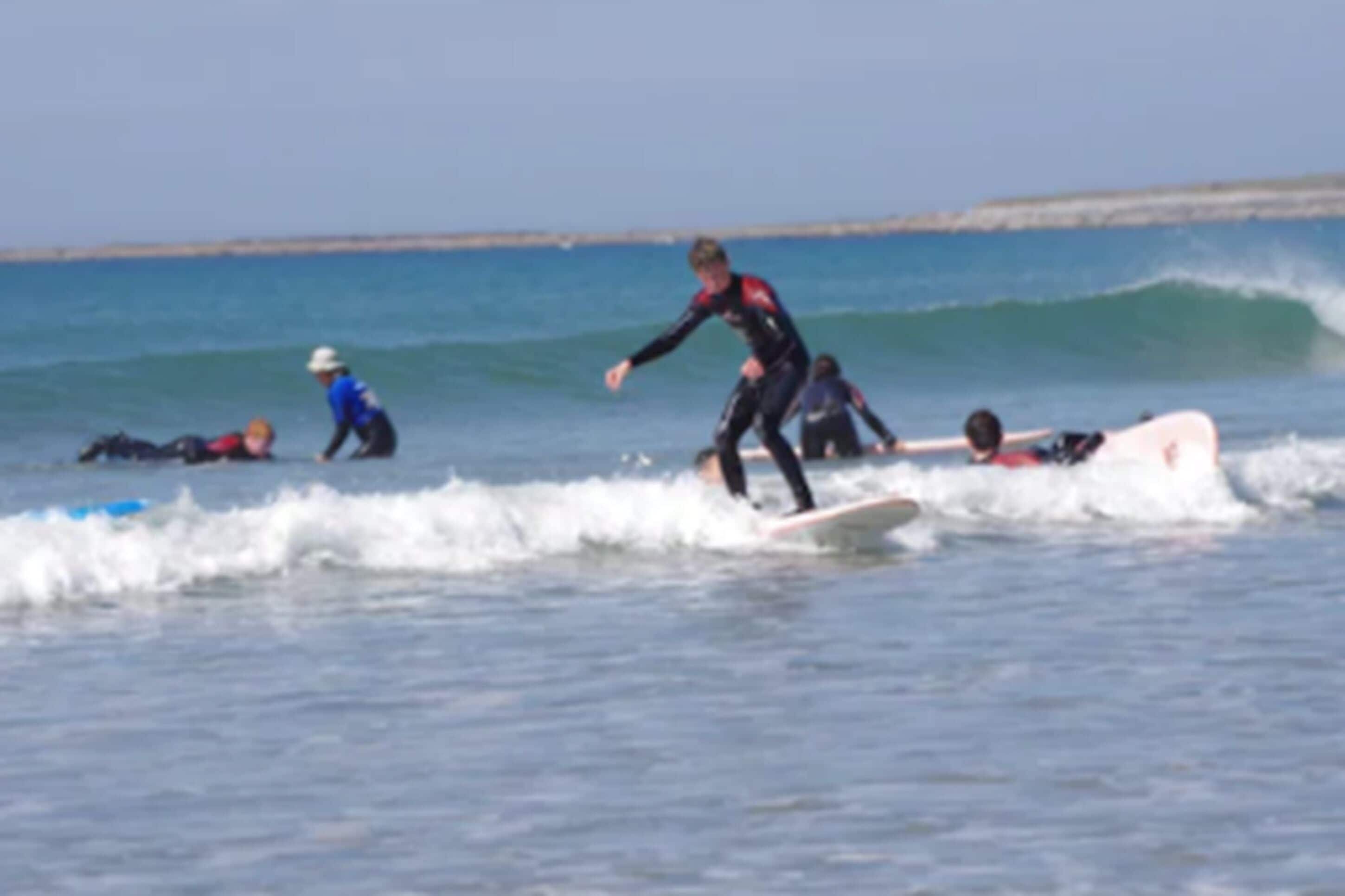 A beach scene with surfers on the water.