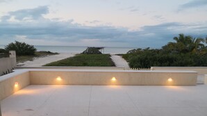 En utomhusterrass med utsikt över stranden och havet.