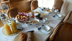 Ein Frühstückstisch gedeckt mit Brot, Müsli, Würzmitteln und Getränken.