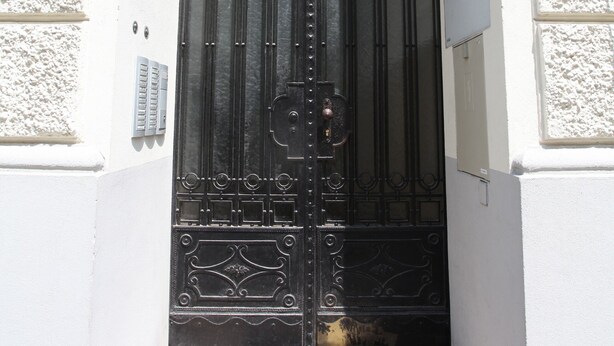 Una reja de hierro forjado negro con una placa de número encima.