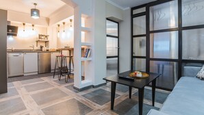A modern living room with a sofa, a coffee table, and a kitchen area in the background. - Ancient Agora Industrial Suite (Thessaloniki)
