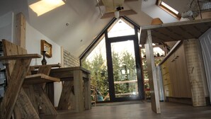A spacious loft with a large skylight, wooden furniture, and a view of trees outside. - Champêtre Park View Apartments (Riga)
