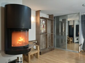 A modern living room with a large fireplace, wooden furniture, and a glass door leading to another room.