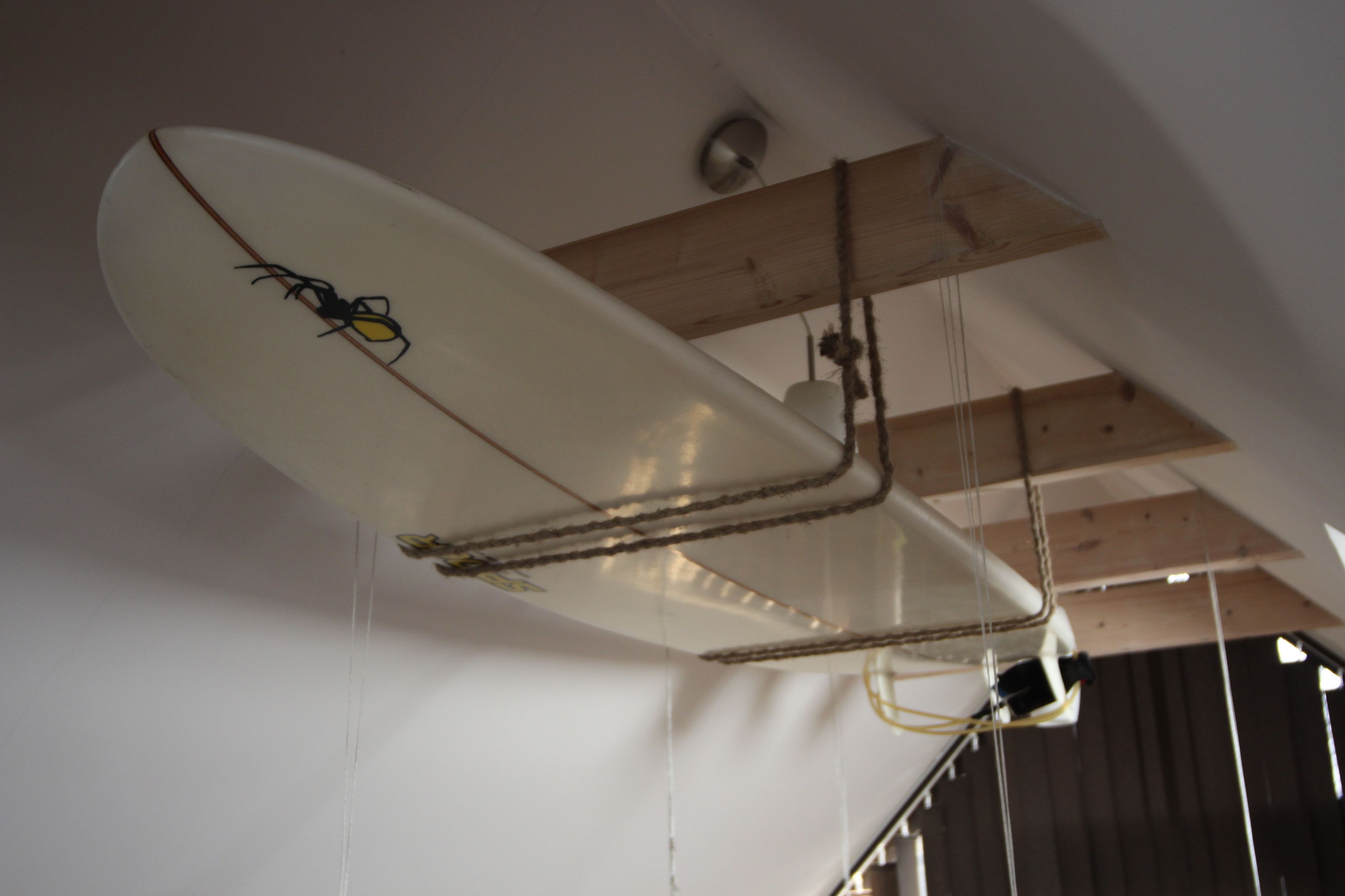 Un techo con una lámpara con forma de tabla de surf y vigas de madera a la vista.