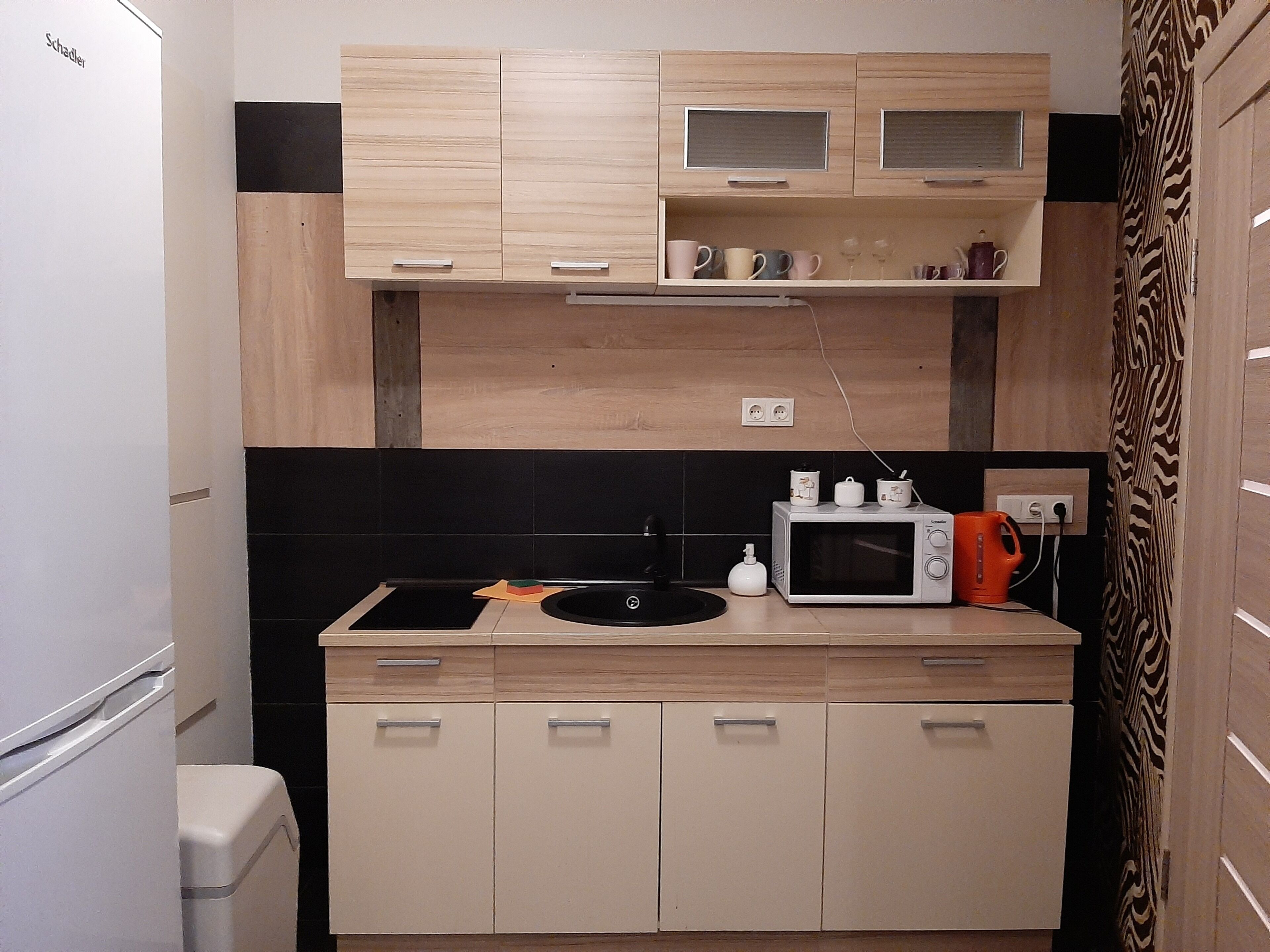 A compact kitchen with a microwave, sink, and cabinets.