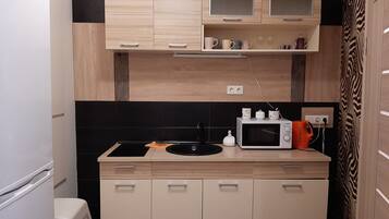 A compact kitchen with a microwave, sink, and cabinets.