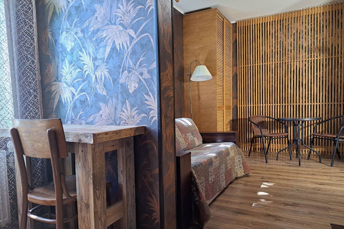 A room with a wooden table and chairs, a sofa, and a lamp.