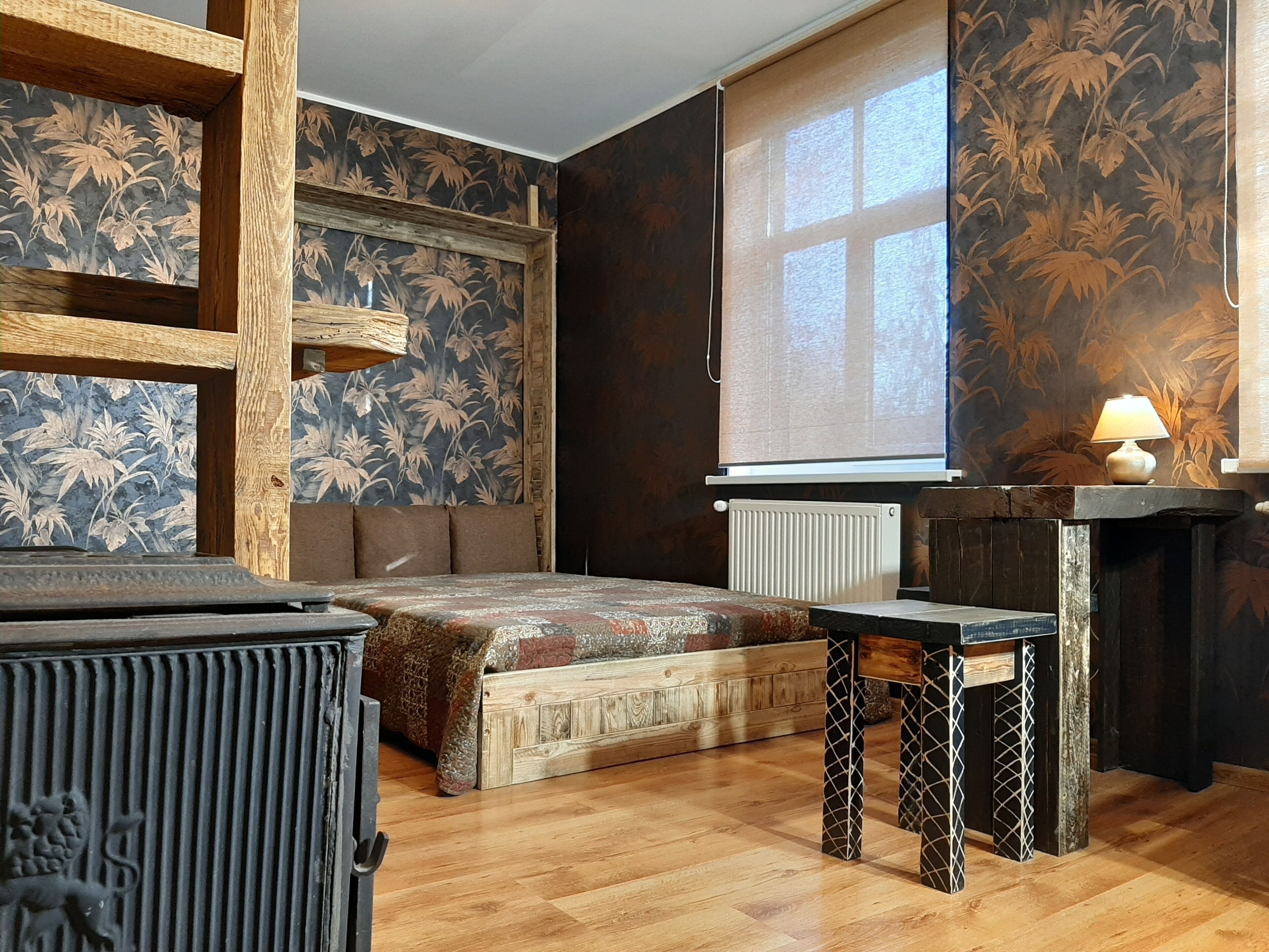 Una habitación con una cama, un banco de madera, una mesa y un radiador.
