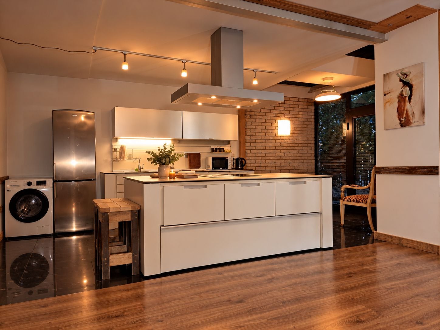 Cocina moderna con una isla central, electrodomésticos integrados y una pared decorativa de ladrillo.