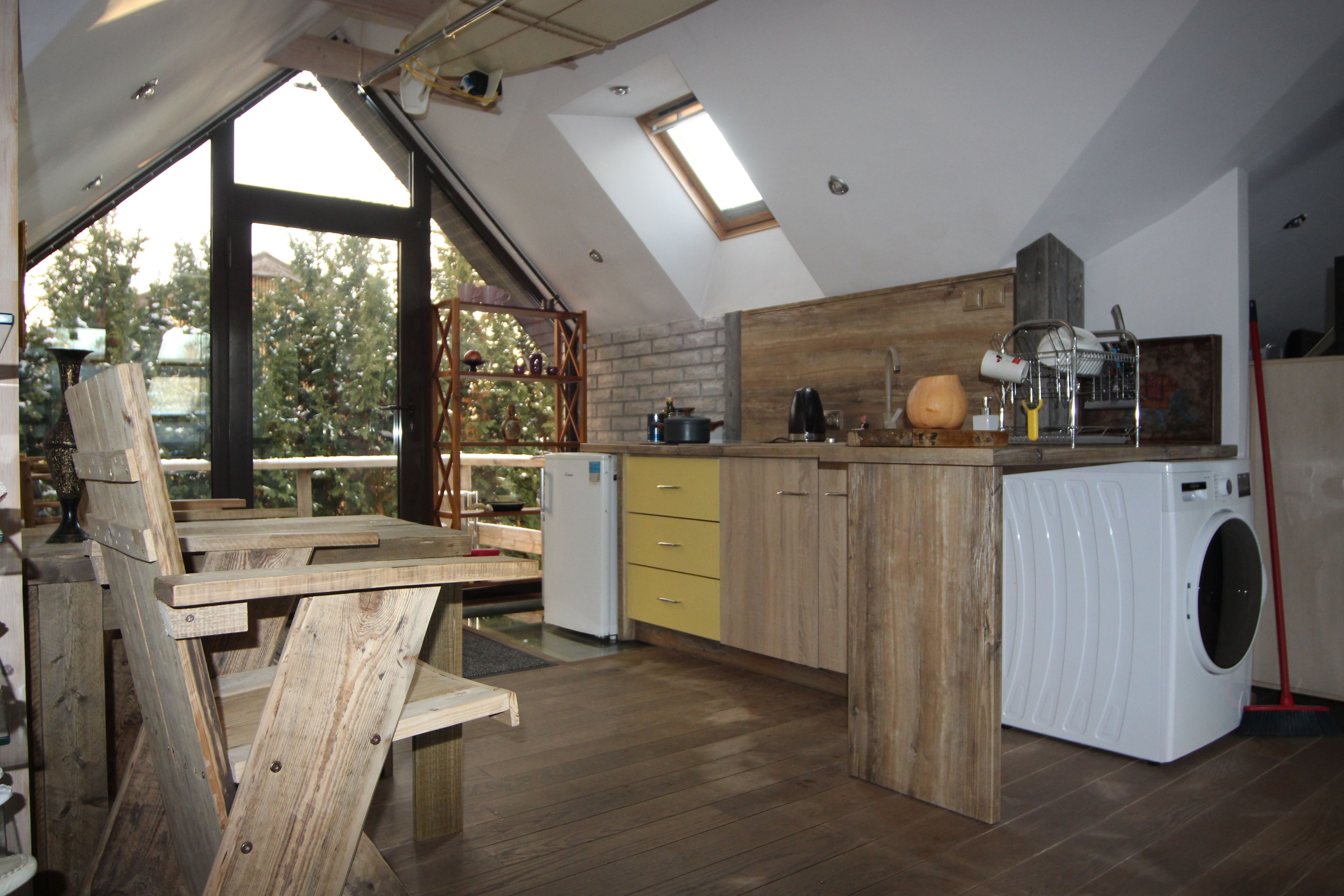 Une cuisine de style industriel, avec des meubles en bois, un lave-linge encastré et une lucarne.