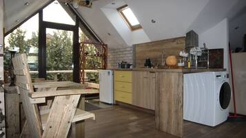 Une cuisine de style industriel, avec des meubles en bois, un lave-linge encastré et une lucarne.