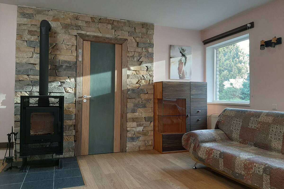 A living room with a stone wall, a fireplace, a sofa, and a window.