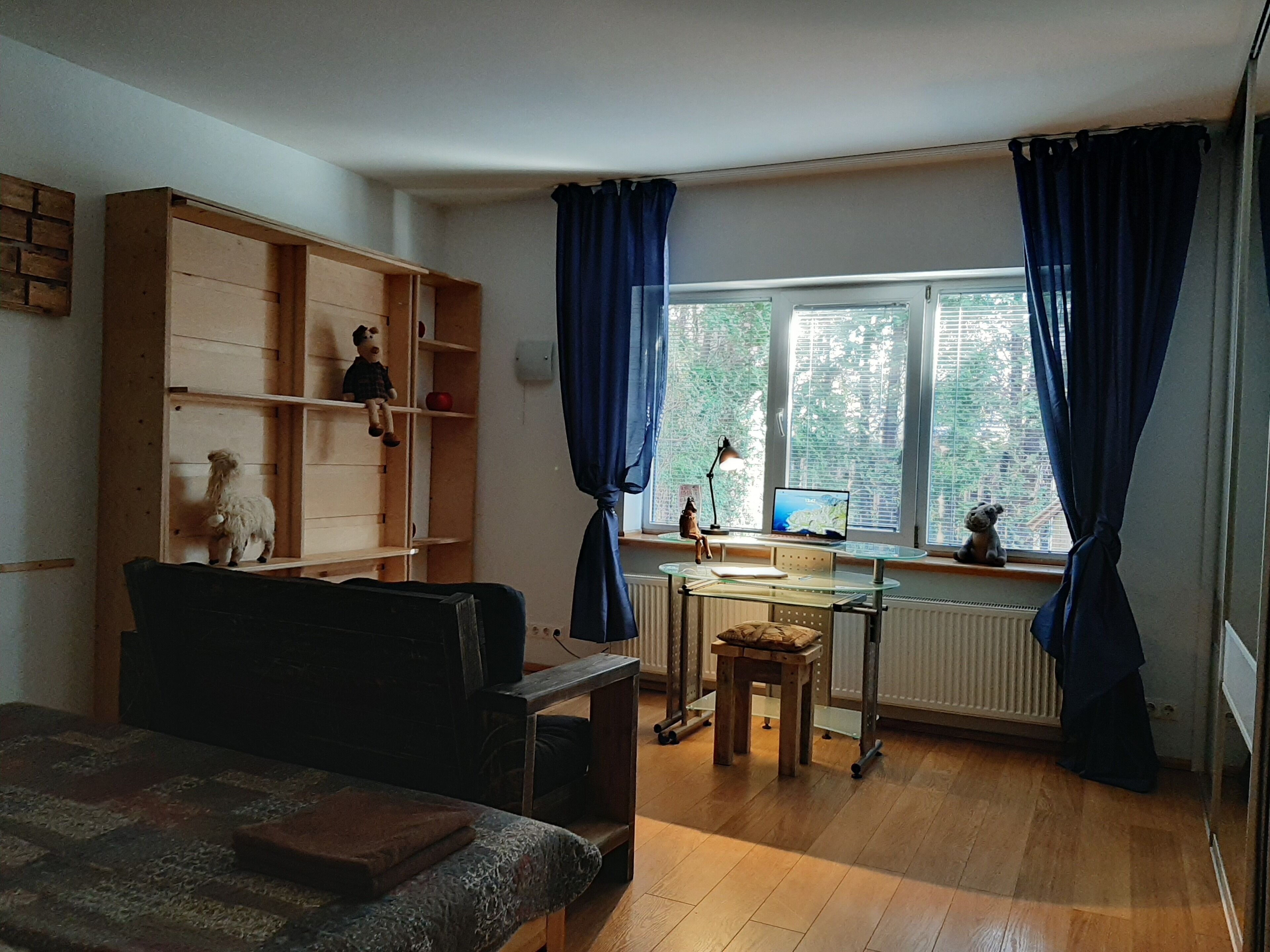 Una stanza con un letto, una scrivania con un computer, una libreria e una finestra con tende.